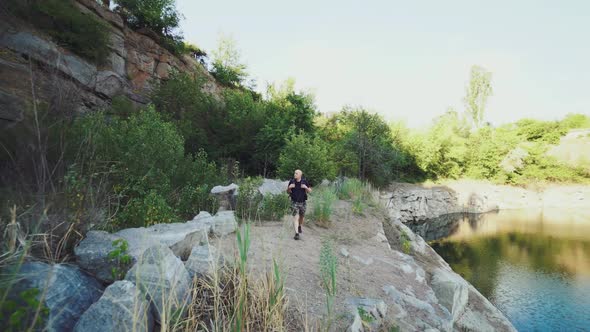 traveler is holding hands for the harnesses of a backpack and walking along the bank