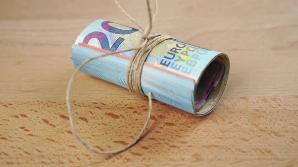 A bundle of Euro currency banknotes with a tied rope goes down 