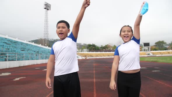 Happy Asian Boy And Girl Takes Off Mask And Running At Stadium 