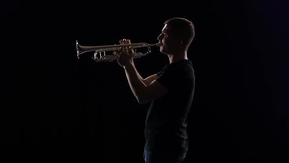 Trumpeter Man Plays on Wind Instrument Melody. Black Studio Background