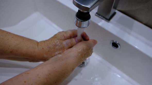 Old Woman Washing hands with soap and hot water at home bathroom sink woman cleansing hand hygiene