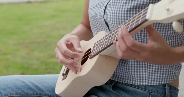 Woman Play a Song on Ukulele and Sitting on The Grass