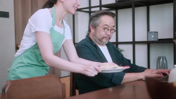 happy monday morning asian mother prepare breakfast for her husband