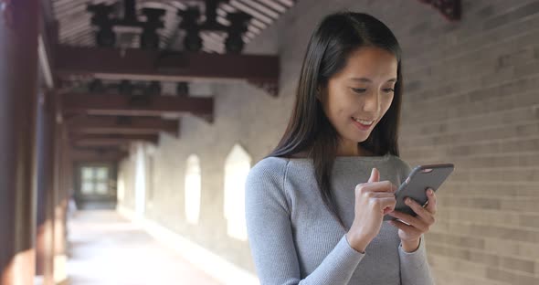 Woman using mobile phone in chinese garden