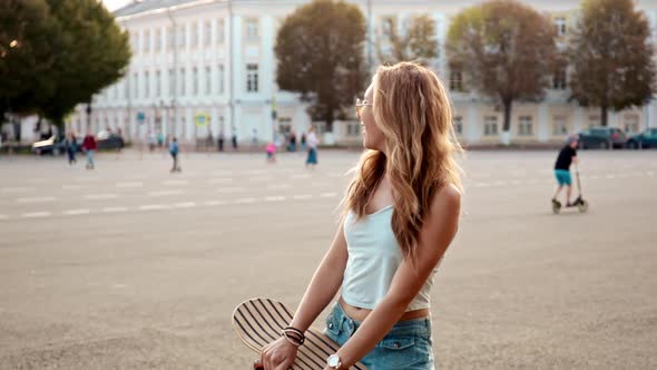 Wide Portrait of a Happy Smiling Skater Girl Sitting in a Skatepark Taking a Moment to Rest and