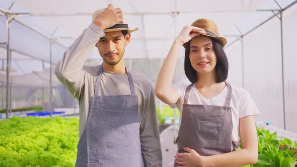 Two Asian couple farmers owner working in vegetables hydroponic farm with happiness.