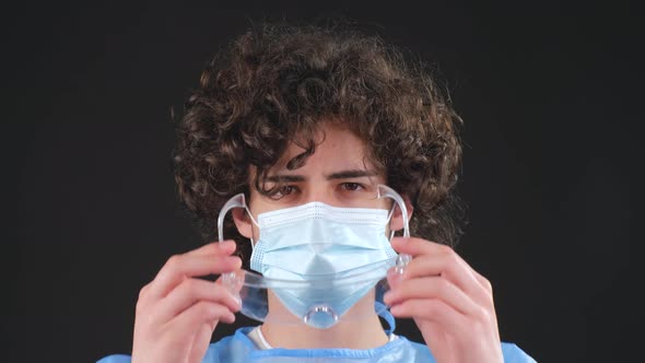 Serious Man in a Blue Medical Coat and Medical Mask Looking at Camera