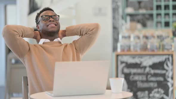 Creative African Man Stretching While Working on Laptop