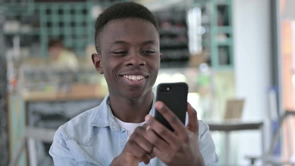 Cheerful African Man Using Smartphone