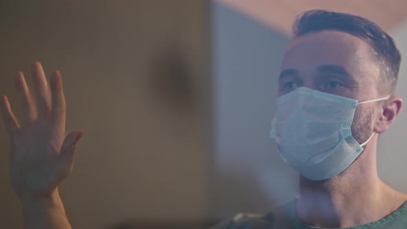 Caucasian Man In Face Mask Standing Near Window