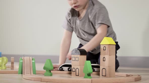 Cute boy plays with a wooden train, takes him across the bridge on flights. Wooden educational toys.