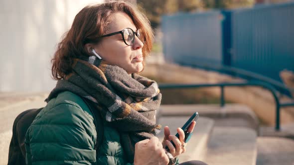 A Young Woman in Glasses Sings Along To the Music in Her Wireless Earphones