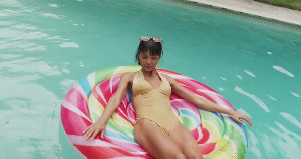 Happy caucasian woman wearing swimming suit with inflatable at swimming pool in garden