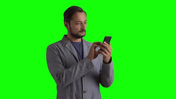 A Man in a Suit Uses a Mobile Phone Against a Green Screen