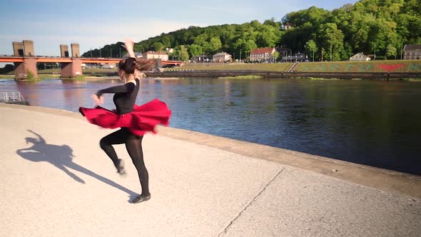 Attractive Caucasian dancer dancing in front of a river in the evening sunshine