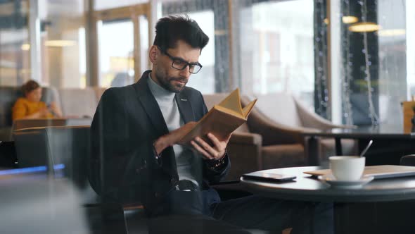 Smart Man Businessperson Reading Book in Cafe Focused on Literature