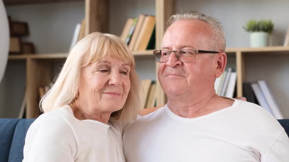 Closeup Portrait of Retired Couple Hugging While Sitting on Couch in Living Room