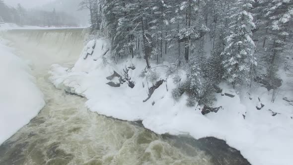 Spectacular winter wonderland scene filmed by drone flying over flowing river