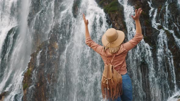 Young Woman Traveler Looking at a Waterfall