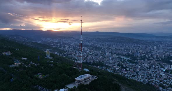 Aerial view of center of Tbilisi under Mtatsminda mountain at sunset. Georgia 2022 summer