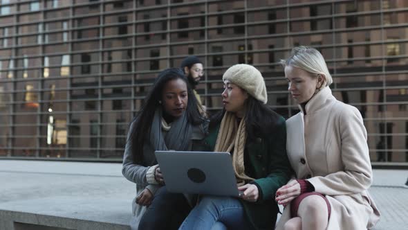 Three Multiracial Young Business Women Working Together on Laptop Outdoors