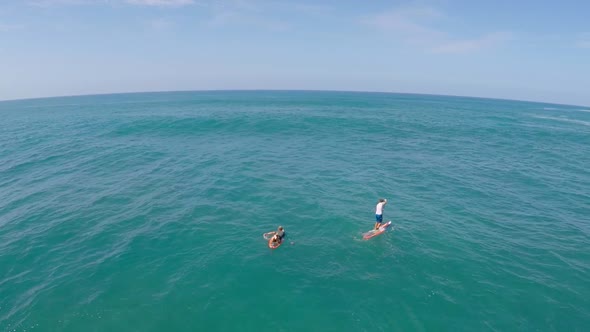 Aerial view of two men sup stand-up paddleboard surfing in Hawaii