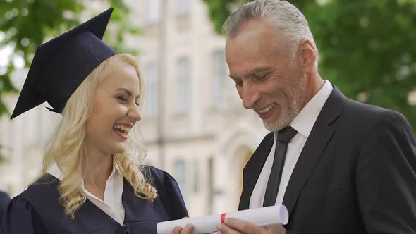 Happy father proud of daughter and congratulating her on education diploma