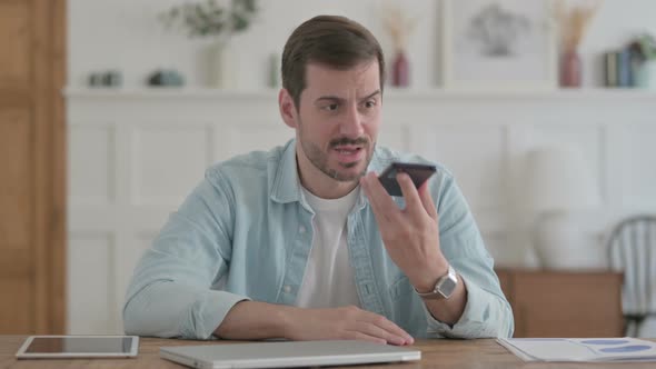 Upset Young Man Talking Angrily on Smartphone in Office