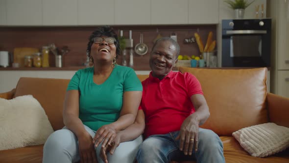 Positive Elderly African Couple Bonding on Sofa