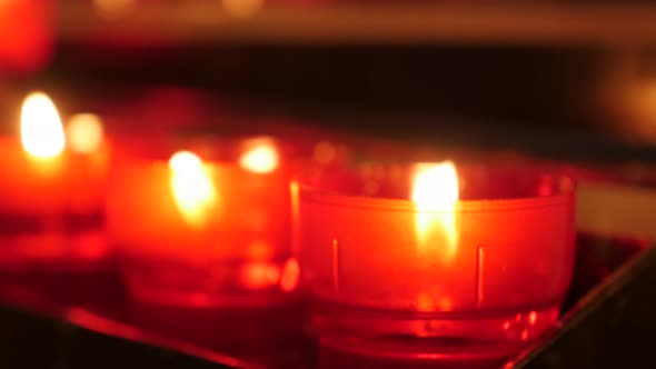 Tilting on Catholic prayer red cup votive candles in candle rack 4K 2160p 30fps UltraHD footage - Lo