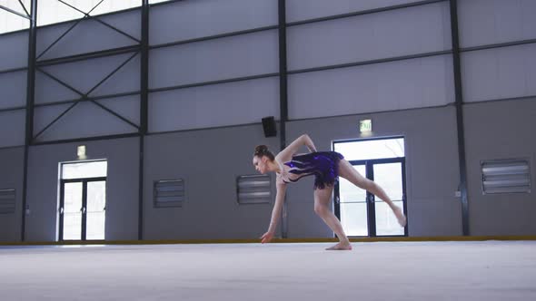 Teenage female gymnast performing at sports hall