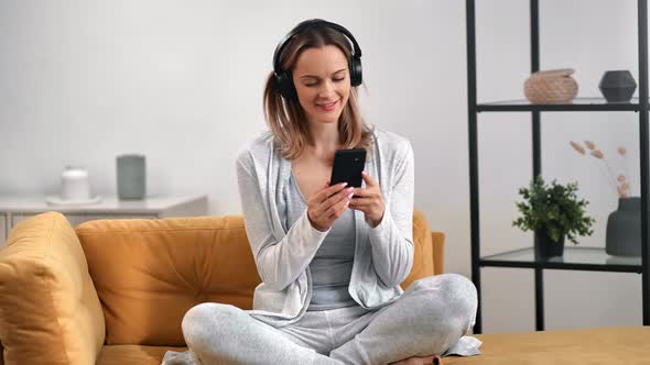 Pleasant Female in Headphones Enjoying Audio Sound Smartphone