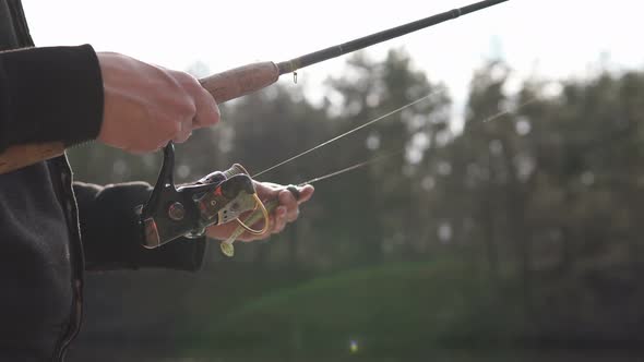 The guy in his free time catches a predatory fish on spinning from the shore. Fishing as a hobby.