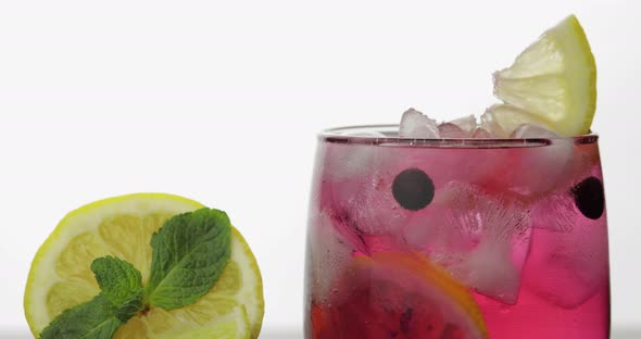 Adding Leaves of Mint in a Glass with Cold Drink, Lime, Lemon, Currants, Ice