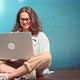 A Young Cheerful Woman in Glasses is Typing on a Laptop - VideoHive Item for Sale