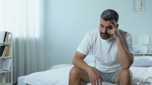 Sad Unemployed Man Sitting in Bedroom, Thinking About Plans for Future Depressed