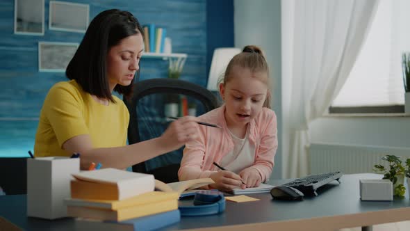 Little Girl Writing on Notebook with Pen While Mother Giving Assistance