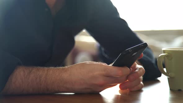 Man relaxing with smartphone and cup of coffee