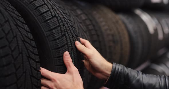 Man Touches Winter Car Tires in a Auto Shop