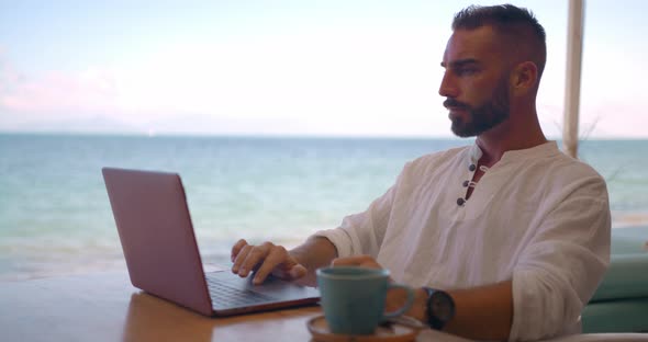 Businessman in White Shirt Having a Cup of Coffe in the Open Summer Cafe and Browsing the Internet