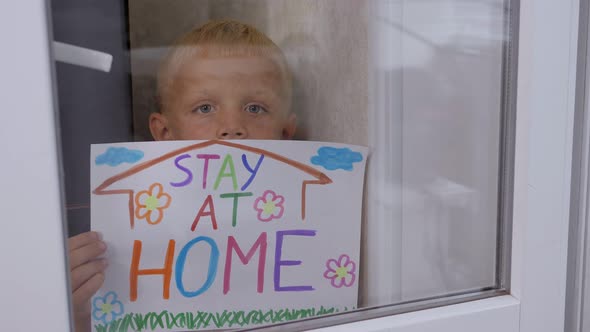 Portrait of a Little Boy Near the Window with the Inscription STAY AT HOME