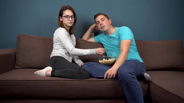 A Woman Feeds a Man Popcorn. The Girl Puts Popcorn in the Man's Mouth. A Couple Is Watching TV