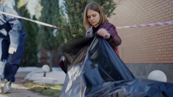 Thoughtful Woman Looking at Dead Corpse As Colleague in Forensics Uniform Entering Crime Scene