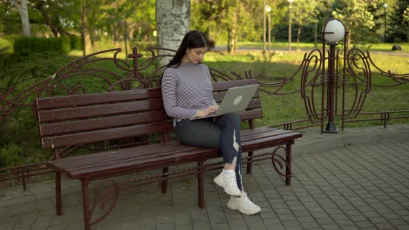 Young Busy Woman Working with Laptop in City Park