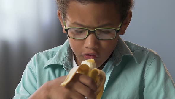 Small Child in Glasses Eating Banana, Lunch Break at School, Healthy Dieting