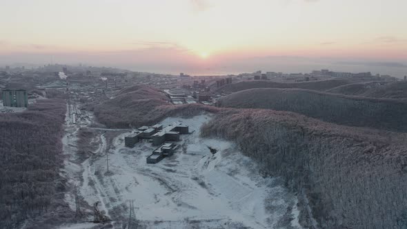 View From a Drone To the Winter Forest and the City at Sunset