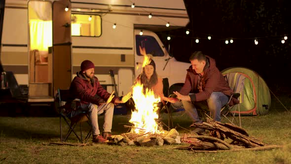 Friends Warming Up Their Hands During a Cold Night at Camp Fire