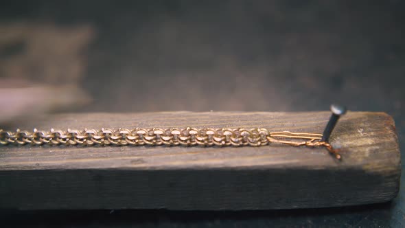 Jeweler Polishes Gold Chain on Wooden Gutter at Table Close