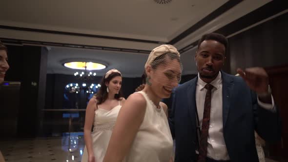 Carefree guests and newlyweds dancing in hall together