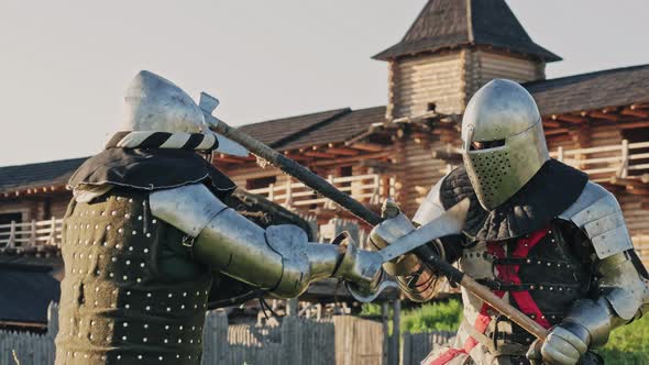 Battle of two knights in armor near wooden fortress. Metal armor medieval of knights